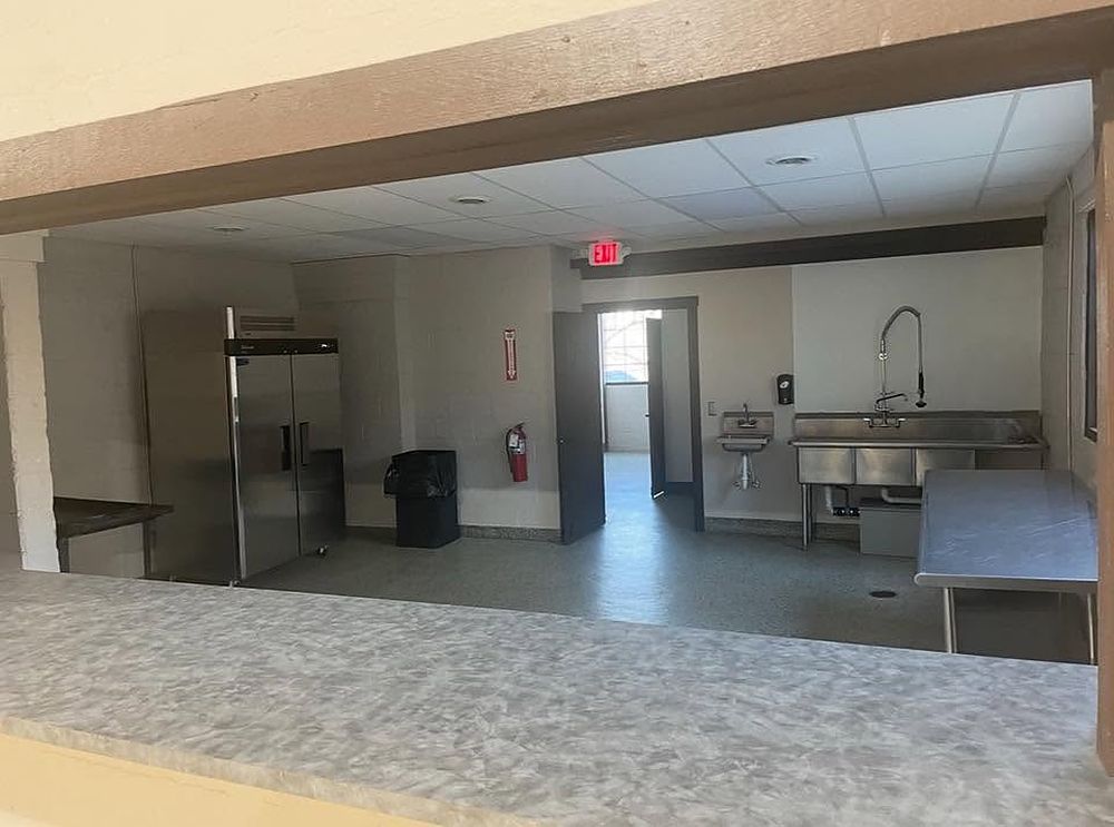 Catering kitchen with commercial refrigerator, sinks and prep tables